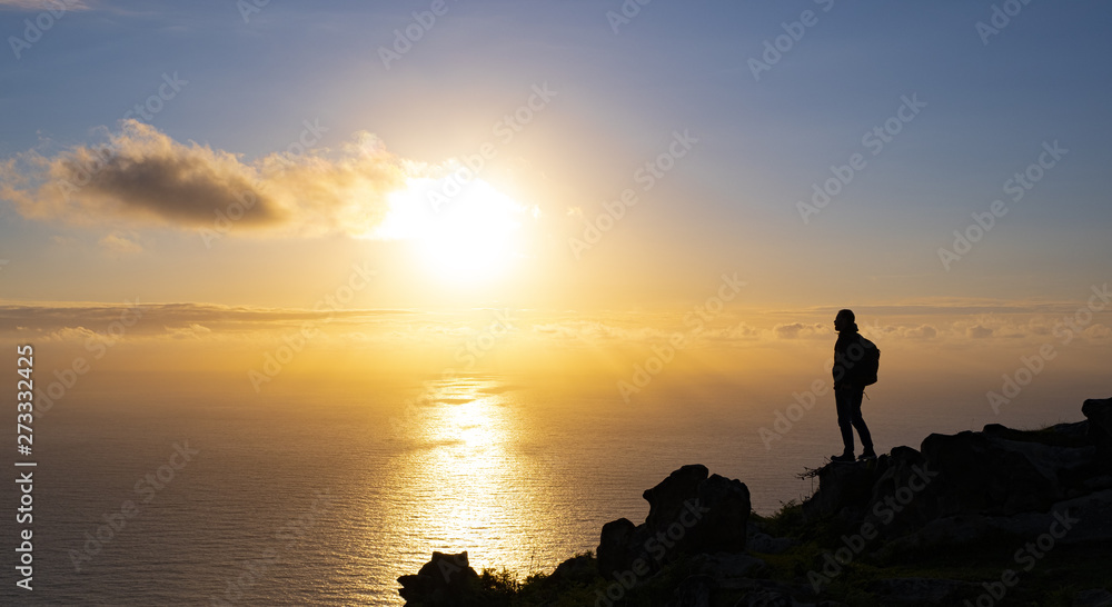Man on top of the mountain watching the sunset over the sea, Basque Country, Spain