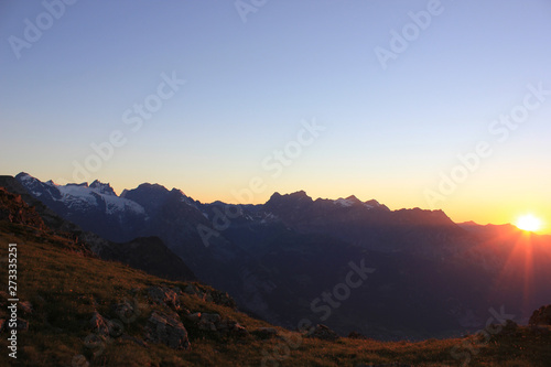 Colorful sunset in the swiss mountains with a raising sun behind the mountains