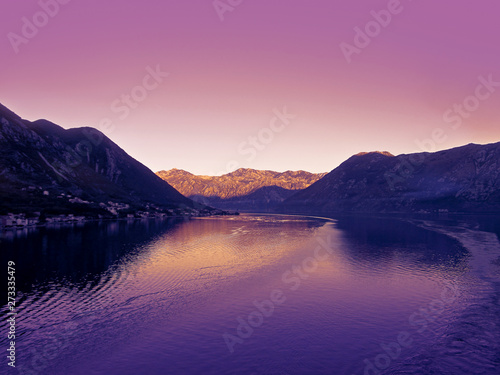 Kotor bay, Montenegro, Europe. Beautiful landscape of the sea, coastline, mountains and sky. View from a cruise ship that leaves a trail of waves on a calm water surface. 