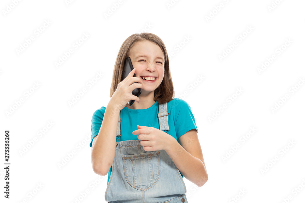 Cute teen girl in denim overalls talking on the phone and laughing. Isolated on a white background. Cute teen girl in denim overalls talking on the phone and laughing. Isolated on a white background.