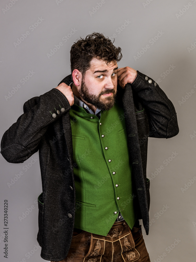 cool man with black hair and black beard with traditional costume is posing in front of grey background cool man with black hair and black beard with traditional costume is posing in front of grey background