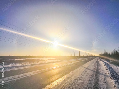 bright rays of the sun in the morning over the snowy road