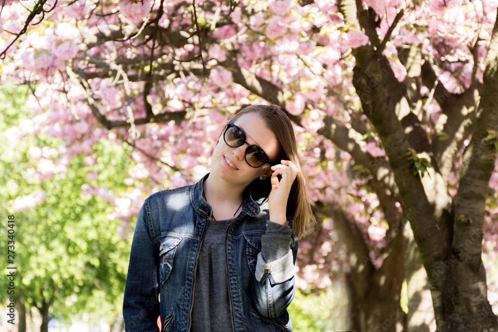 teen girl with glasses against the background of blossoming sakura