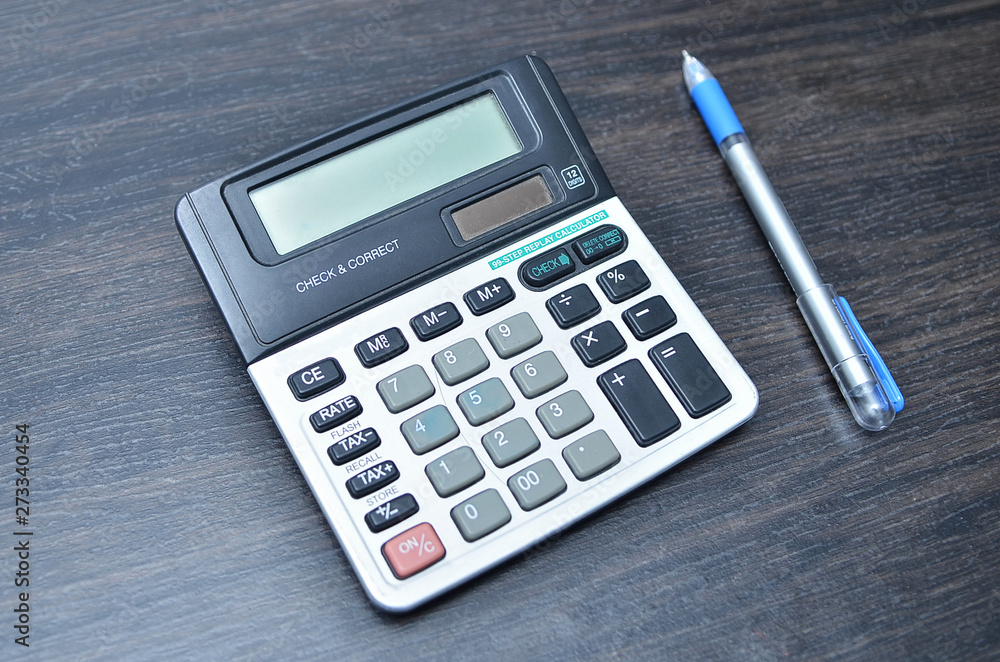 Calculator with pen on wood board background Calculator with pen on wood board background