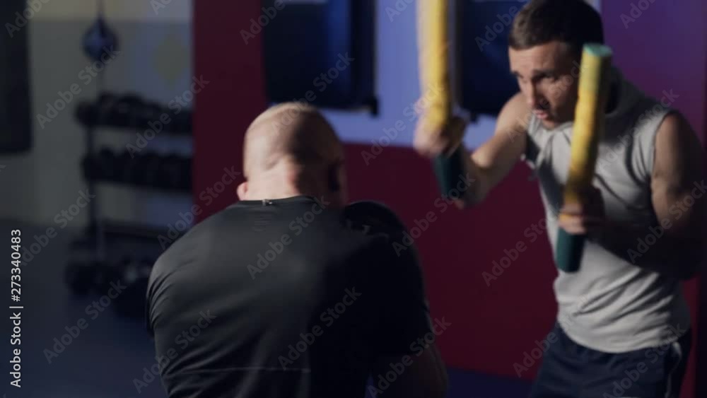 Coach trains boxer in gym, work out kick and defense, slow motion. Coach trains boxer in gym, work out kick and defense, slow motion.