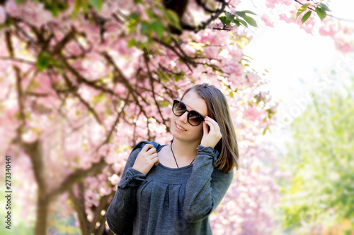 teen girl with glasses against the background of blossoming sakura