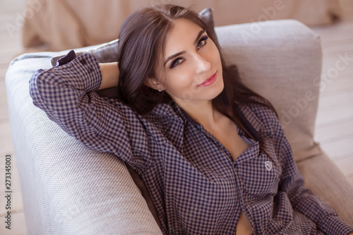 Beautiful brunette woman lies in on the couch in the living room, and looks at the frame. Life style.