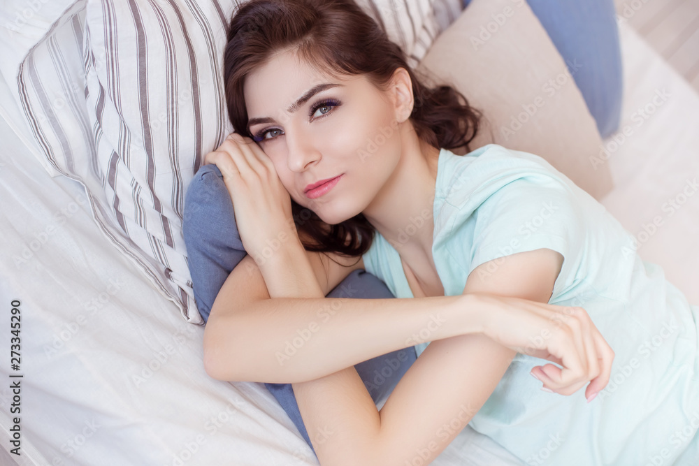 Beautiful brunette woman lying in bed on a bed in a T-shirt and shorts, close-up portrait. Sexy adult woman of 30 years. Life style. Beautiful brunette woman lying in bed on a bed in a T-shirt and shorts, close-up portrait. Sexy adult woman of 30 years. Life style.