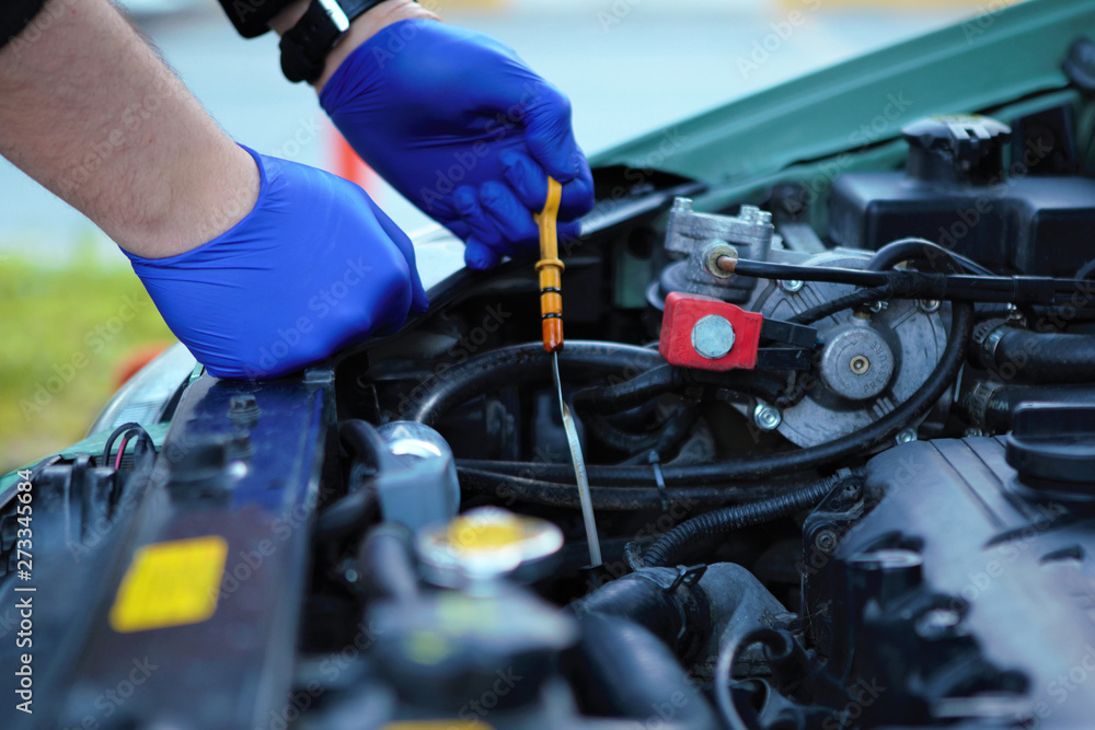 Car Mechanic Checking the Cars Oil Level with a Dipstick Car Mechanic Checking the Cars Oil Level with a Dipstick
