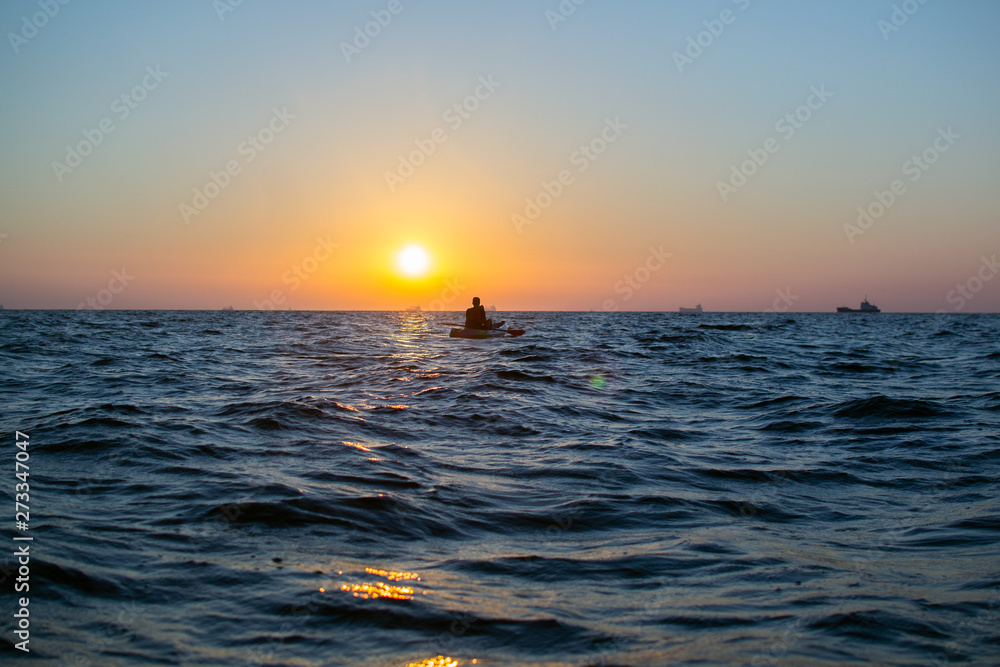 On a warm summer morning, a person meets the sunrise and kayaks. Sports concept On a warm summer morning, a person meets the sunrise and kayaks. Sports concept