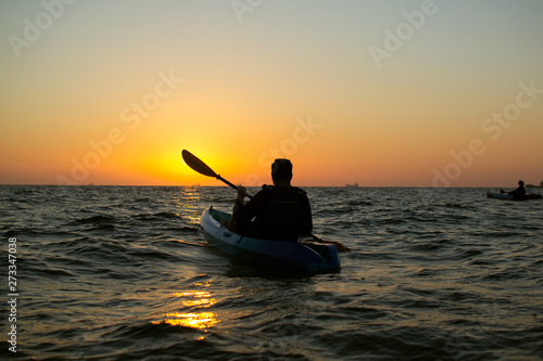 On a warm summer morning, a person meets the sunrise and kayaks. Sports concept
