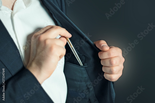 businessman in a suit taking or putting  a pen from the inside pocket of his jacket