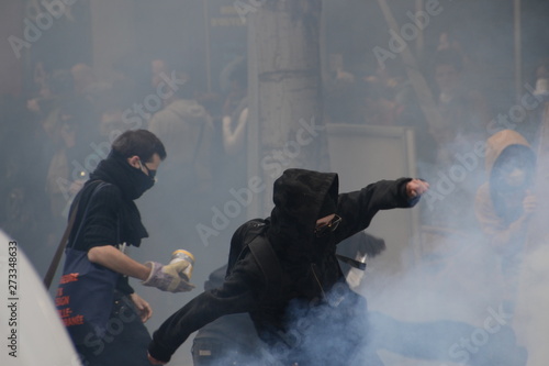 Masked protesters throw projectiles at police in response to tear gas