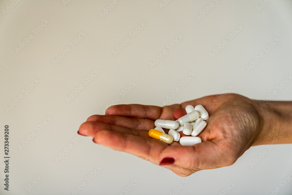 Many pills in different colors presented on open hand of a girl with red fingernails and white background Many pills in different colors presented on open hand of a girl with red fingernails and white background