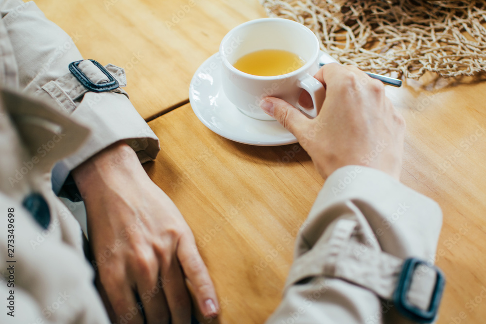 Meeting friends in cafe. The girl drinks tea, coffee in a cafe and touches the cup with her hands, close-up, during meeting with friend Meeting friends in cafe. The girl drinks tea, coffee in a cafe and touches the cup with her hands, close-up, during meeting with friend