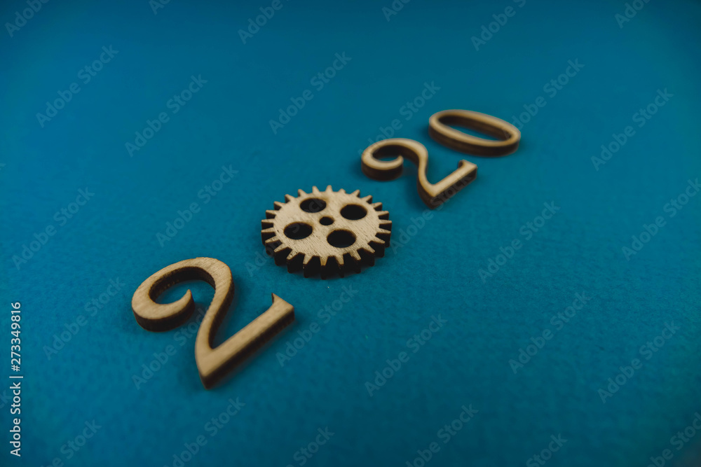 2020 number from wooden numbers on a blue background with scattered stars gears and flags around