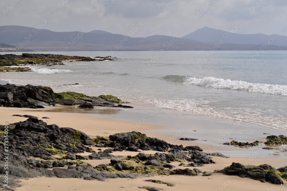 Rocky ocean beach with mountains on background. Costa Calma, Fuerteventura, Canary Islands Rocky ocean beach with mountains on background. Costa Calma, Fuerteventura, Canary Islands