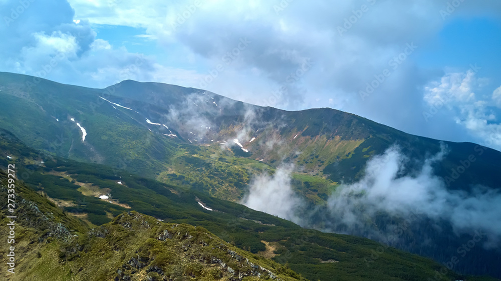 Mountain ridge with rocky outcrops. Panoramic view from the top of the ridge on background of valley. Carpathian Mountains