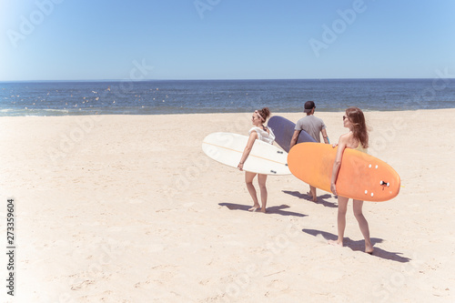 Fototapeta Naklejka Na Ścianę i Meble -  Boys and girls teen surfers with surfboards
