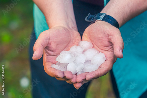 Man hand holding a hail after hailstorm