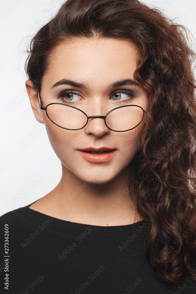 Portrait of a beautiful intelligent woman with curly hair and spectacles. Studio photo session