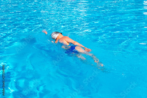 Woman with swimsuit swimming on a blue water pool.