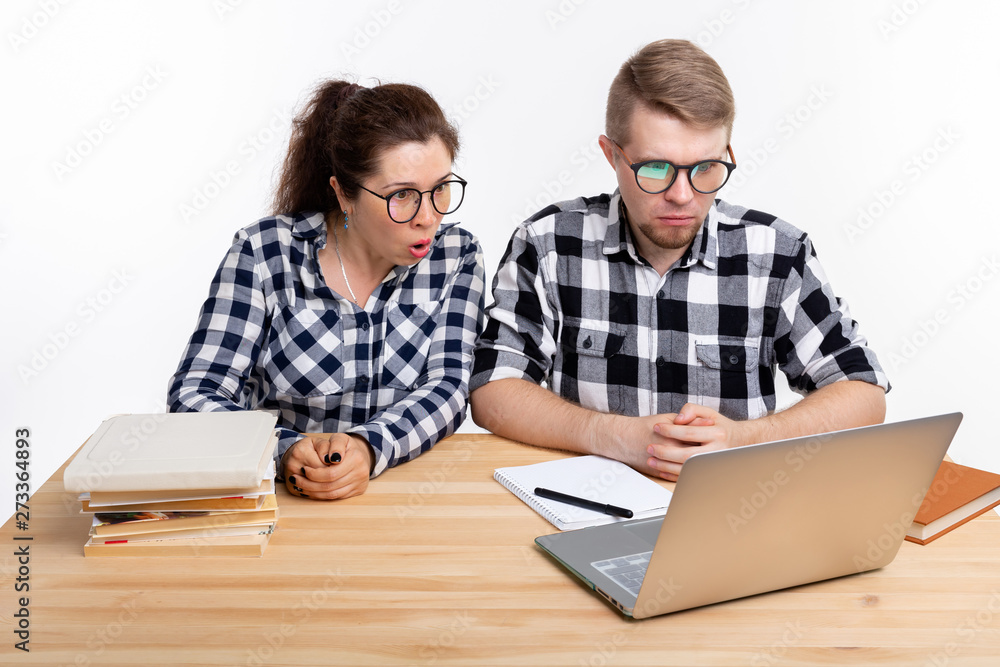 Education, students, people concept - a couple of teens in glasses are scared of something during looking in laptop Education, students, people concept - a couple of teens in glasses are scared of something during looking in laptop