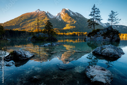 Fantastic sunrise at Hintersee lake. Beautiful scene of trees on a rock island during Spring