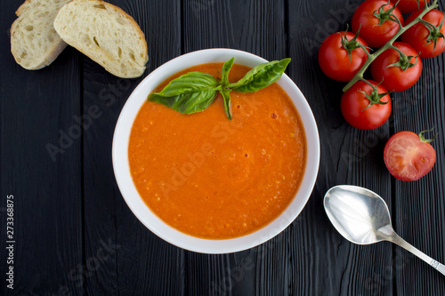 Tomato soup in the white bowl on the black wooden background.Top view.Copy space.