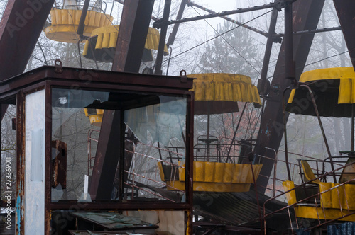 rust ferris wheel attraction in fog in winter abandoned amusement park overgrown with trees in Pripyt, Chernobyl zone of alienation