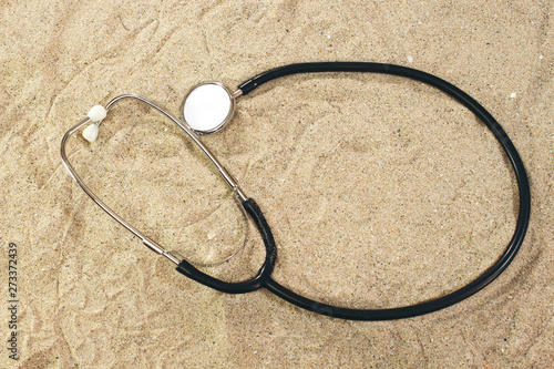 Stethoscope in sand, summer concept