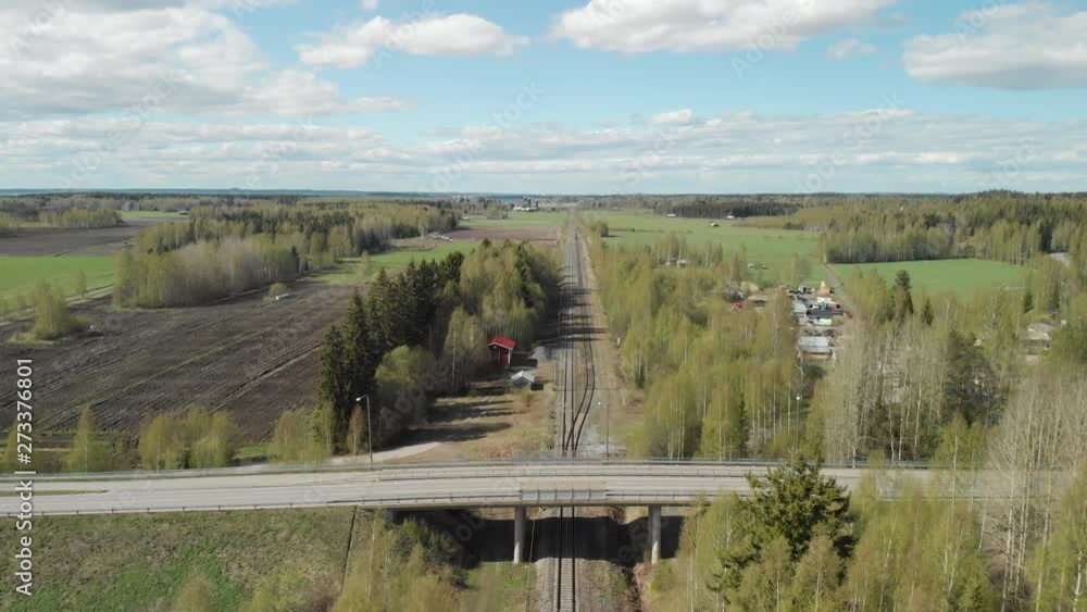 Aerial, reverse, drone shot, above a railway, overlooking buildings and a bridge, surrounded by spring color forest, on a sunny, spring day, in Joensuu, Pohjois-Karjala, Finland Aerial, reverse, drone shot, above a railway, overlooking buildings and a bridge, surrounded by spring color forest, on a sunny, spring day, in Joensuu, Pohjois-Karjala, Finland