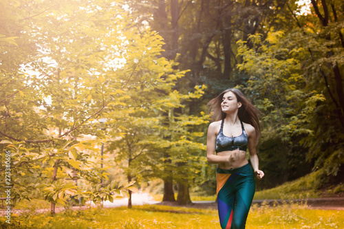 Pretty sporty woman jogging at park in sunrise light