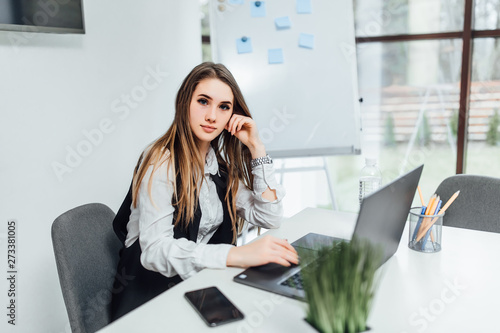 Beautiful clever and cute owner of big company has online meeting with international business partners, she is sitting at the table at workstation ...