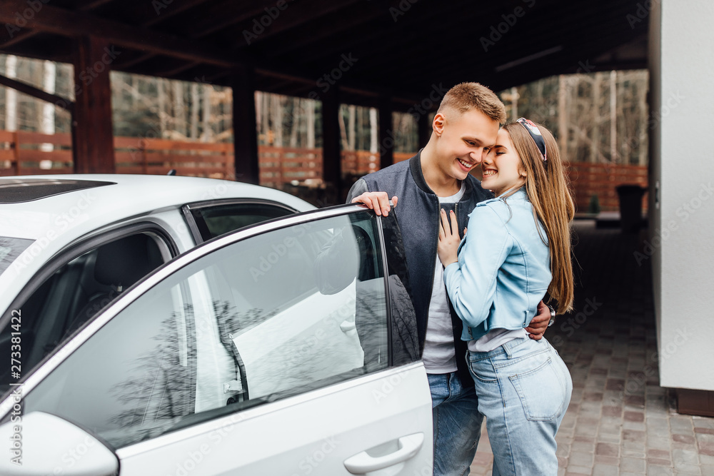 Romantic couple is standing near new white car on home and hugs. Romantic couple is standing near new white car on home and hugs.