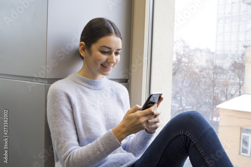 young female student using a smartphone, smiling, listening to music Free Download young female student using a smartphone, smiling, listening to music - GFXLoad