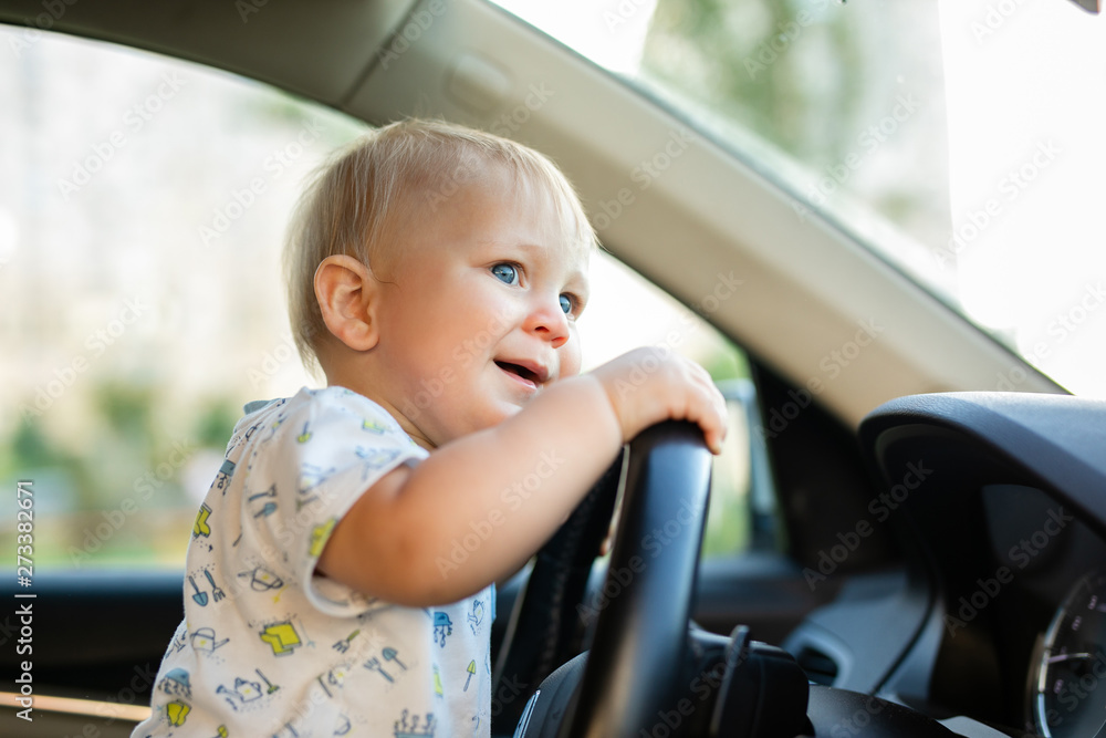 Cute little baby boy driving big car, holding steering wheel,smiling and looking forward with interest. Childhood game and dreams. Cute little baby boy driving big car, holding steering wheel,smiling and looking forward with interest. Childhood game and dreams.