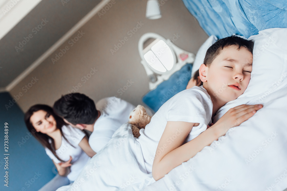 Family and his little baby are peacefully sleeping together in bed. Family and his little baby are peacefully sleeping together in bed.