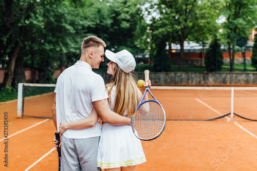 Young couple having fun standing together on the tennis court relaxing after the match outdoors.. © Тарас Нагирняк