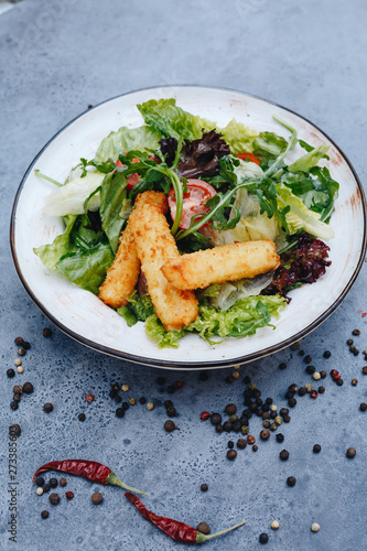 appetizing salad with fried cheese and herbs on a gray background with copy space