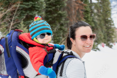Young Mom Snowshoeing with her Baby in a Backpack in a Beautiful Mountain Setting