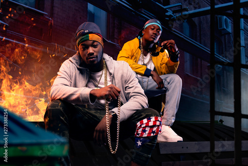 Vászonkép Two black rappers in caps sitting by the fire
