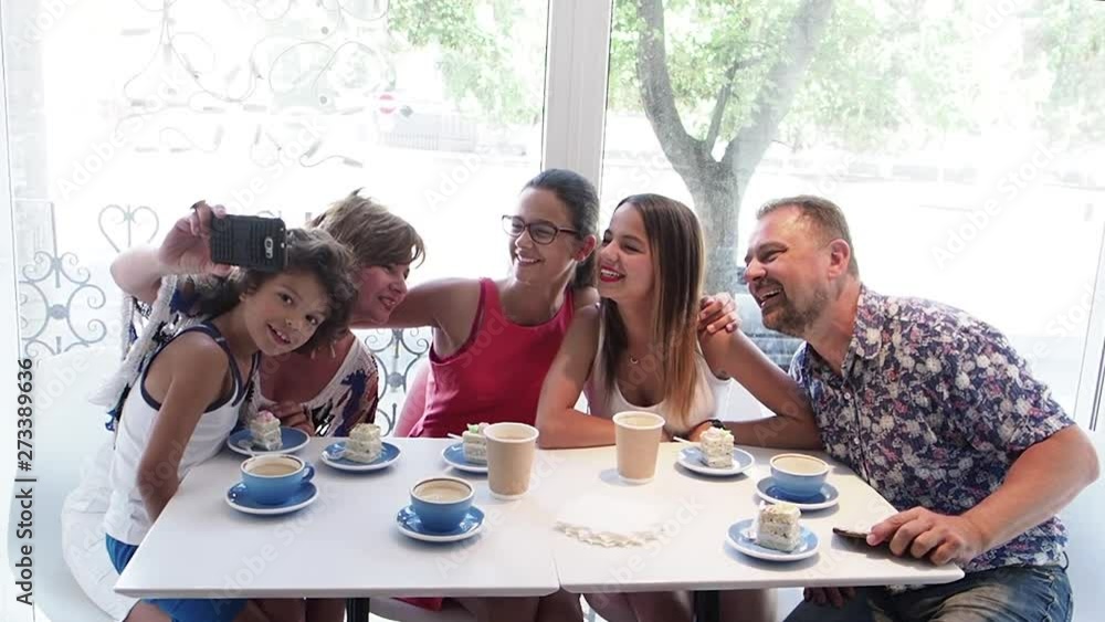 Cheerful lovely family sitting together by the table in cafe while making selfie. Slow Motion Cheerful lovely family sitting together by the table in cafe while making selfie. Slow Motion