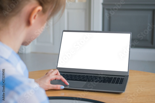 Mockup image of woman using touchpad of grey laptop with white blank screen on wooden table in home interior. Mock up, copyspace, freelance workspace, template, entertainment and technology concept 