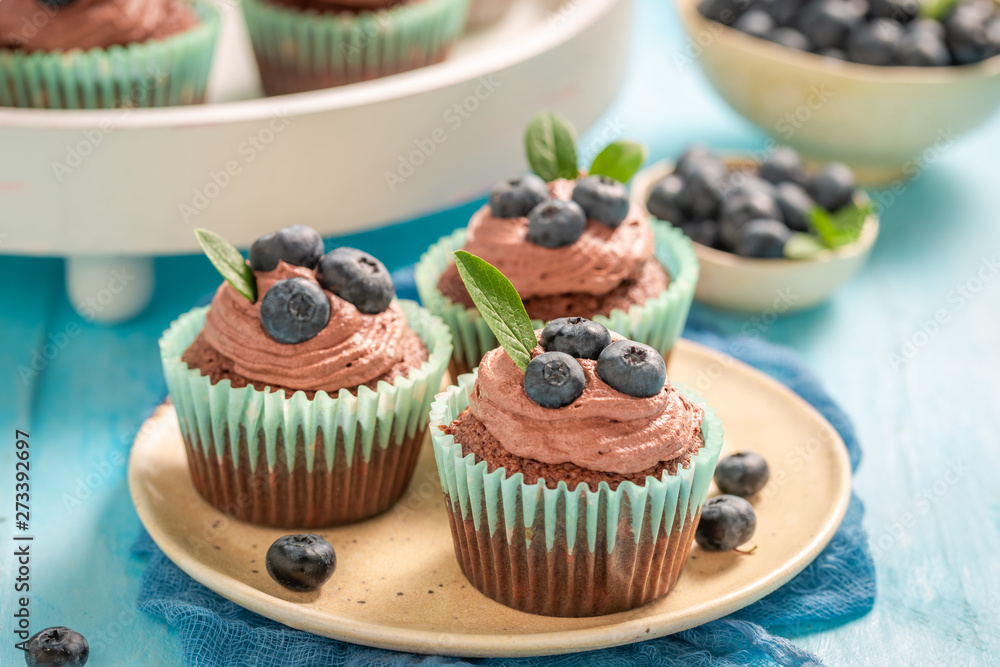 Muffins with chocolate cream and blueberries on blue table