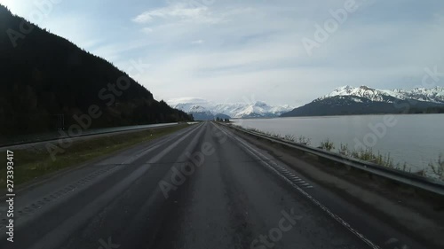 POVin double time 2X; Driving along Turnagain Arm of Cook Inlet and Alaska Railroad tracks on Seward Highway in Alaska, crosses Twentymile River with Chugach Mountains in Background photo