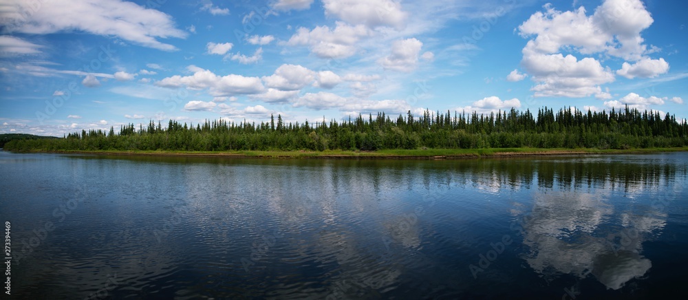 Fototapeta premium Reflection of blue shy with clouds in River, with forrest between river and sky