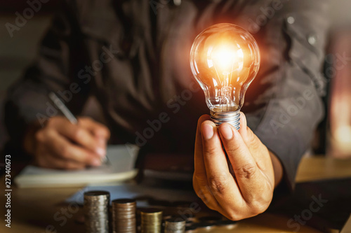 businessman holding light bulb with money stack.saving energy power concept