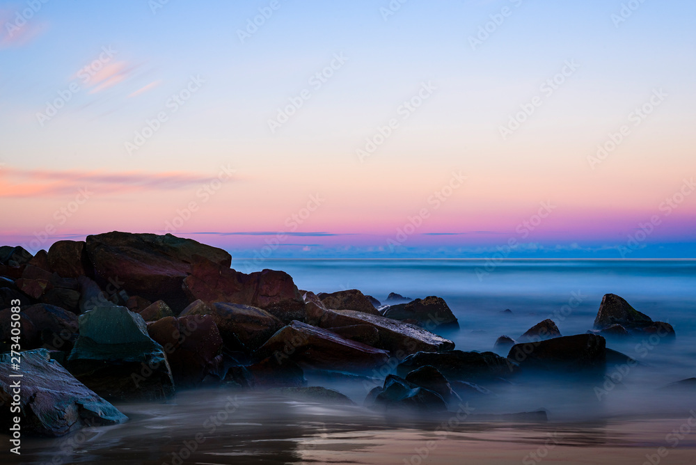Landscape with colorful sky, ocean and rocks, long exposure just after sunset shot at Urunga Beach, Australia.