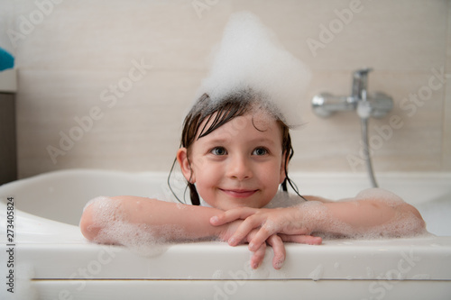 Leinwand Poster little girl in bath playing with foam